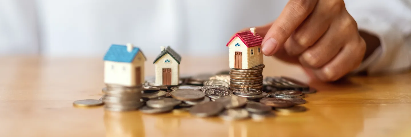 Model houses stacked on coins